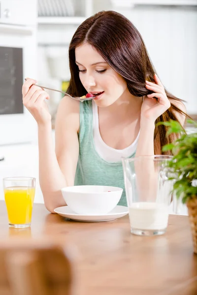 Flickan äta läckra spannmål och apelsinjuice — Stockfoto