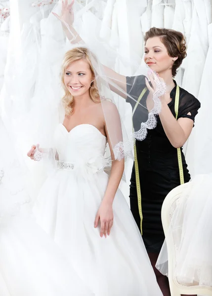 Assistant de magasin met voile de mariage sur la tête de la mariée — Photo