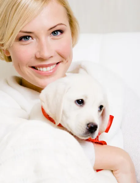 Labrador kadın holding köpek yavrusu kırmızı kurdele ile — Stok fotoğraf