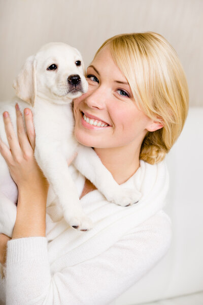 Woman keeping white puppy near her face