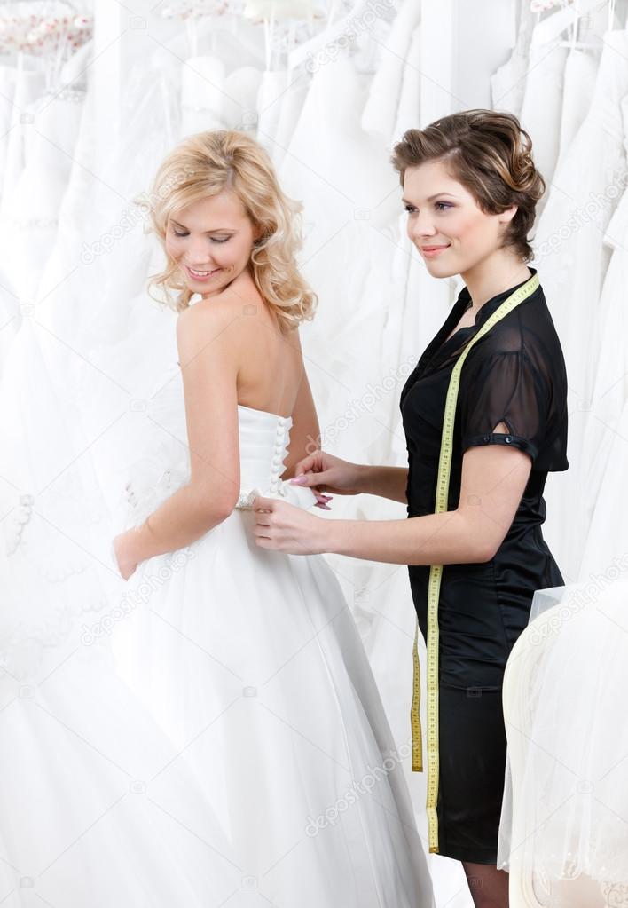 Shop assistant helps to the bride