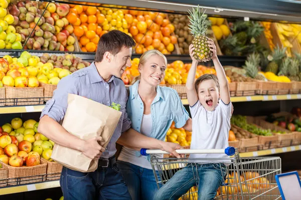 Familie tegen planken van vruchten heeft winkelen — Stockfoto