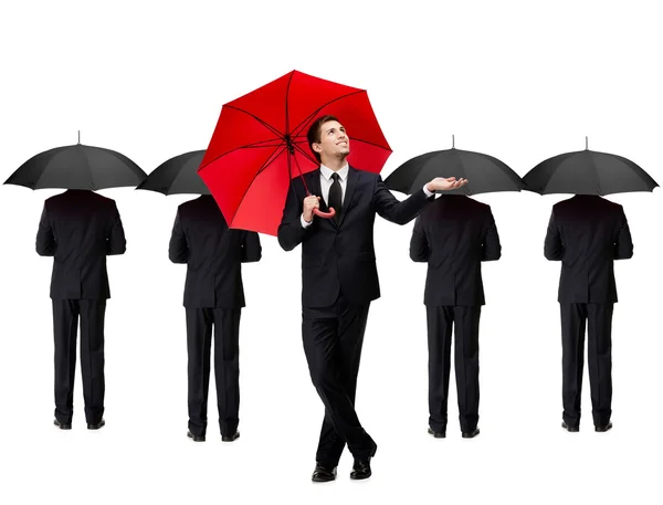Mann mit rotem Regenschirm und Menschen mit Regenschirmen im Rücken — Stockfoto