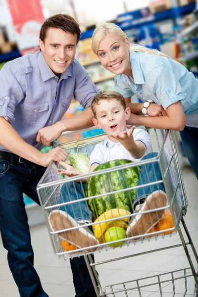 Family drives cart with food and son sitting there — Stock Photo, Image