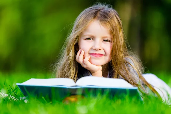 Fille lit livre intéressant sur l'herbe — Photo