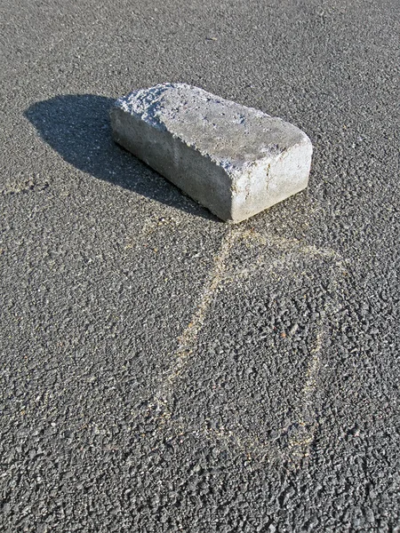 Um tijolo branco abandonado com silhueta em asfalto cinza . — Fotografia de Stock