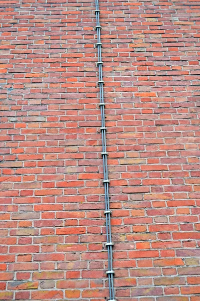 Dlouhý kovový drát (hromosvodu) na cihlové zdi, průmyslové. — Stock fotografie