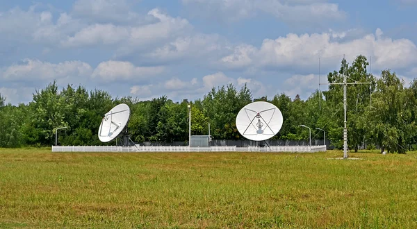Satelliet antennes, groene bomen en onweer blauwe hemel. — Stockfoto