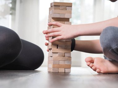 Anne ve çocuk evde Jenga oynuyorlar.
