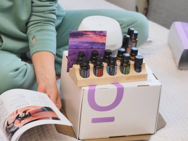 Genç kadın bir sağlık konferansında bir kutu Doterra 'nın gerekli yağlarını açıyor. Belarus, Minsk, 2021.