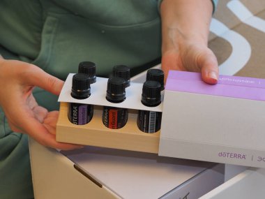 Genç kadın bir sağlık konferansında bir kutu Doterra 'nın gerekli yağlarını açıyor. Belarus, Minsk, 2021.