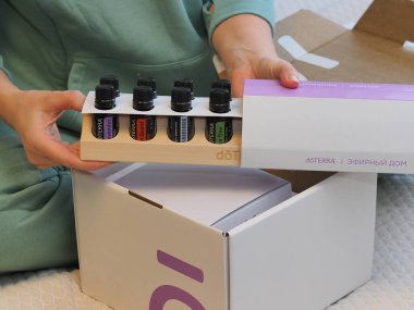 Genç kadın bir sağlık konferansında bir kutu Doterra 'nın gerekli yağlarını açıyor. Belarus, Minsk, 2021.