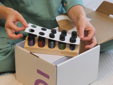 Genç kadın bir sağlık konferansında bir kutu Doterra 'nın gerekli yağlarını açıyor. Belarus, Minsk, 2021.