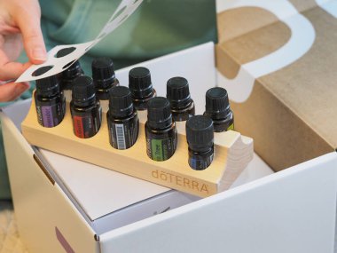 Genç kadın bir sağlık konferansında bir kutu Doterra 'nın gerekli yağlarını açıyor. Belarus, Minsk, 2021.