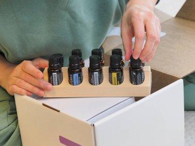 Genç kadın bir sağlık konferansında bir kutu Doterra 'nın gerekli yağlarını açıyor. Belarus, Minsk, 2021.