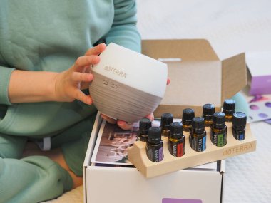 Genç kadın bir sağlık konferansında bir kutu Doterra 'nın gerekli yağlarını açıyor. Belarus, Minsk, 2021.