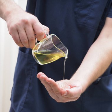 Adam masör eline yağ damlatıyor.