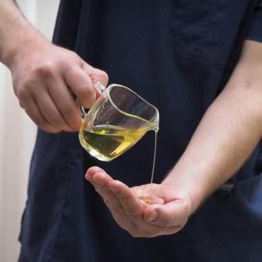 Adam masör eline yağ damlatıyor.