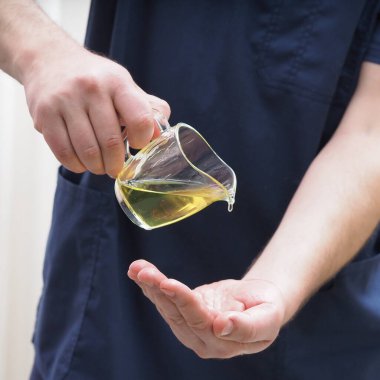 Adam masör eline yağ damlatıyor.