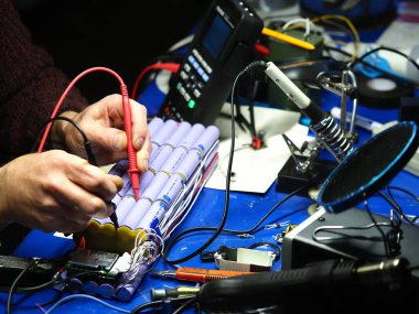 .Belarus, Minsk, 2022 Mobiletin pili bir atölye ustası tarafından tamir ediliyor.