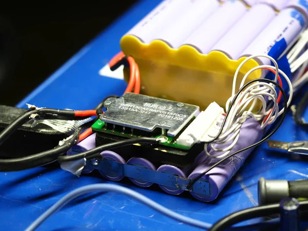 .Belarus, Minsk, 2022 Mobiletin pili bir atölye ustası tarafından tamir ediliyor.