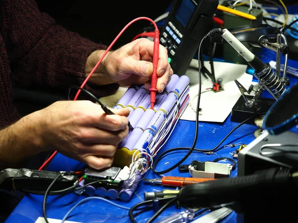 .Belarus, Minsk, 2022 Mobiletin pili bir atölye ustası tarafından tamir ediliyor.