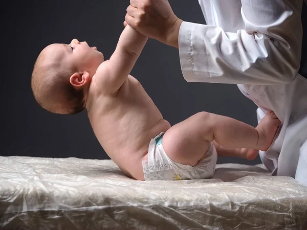 Médico Levanta Las Manos Del Bebé Acostado Mesa Comprobando Los —  Fotos de Stock