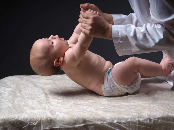 수술대 아기의 들어올리는 의사는 신생아의 신경을 검사한다 — 스톡 사진
