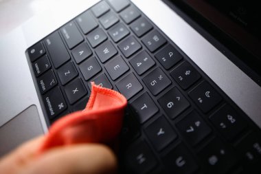 Belarus, Minsk, 2022 MacBook Pro 2021 'in sorunlu klavyesine yapışmış bir insan eliyle bir bez parçasıyla silinmiş.