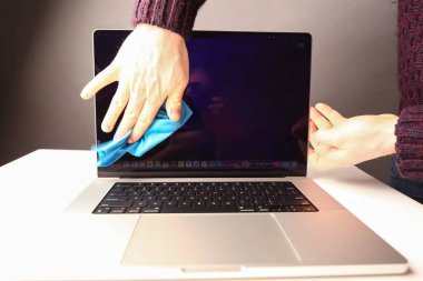 Belarus, Minsk, 2022 MacBook Pro 2021 'in sorunlu klavyesine yapışmış bir insan eliyle bir bez parçasıyla silinmiş.
