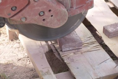İnşaat işçisi elektrik kesicisiyle beton tuğla kesiyor. Belarus, Minsk, 2016