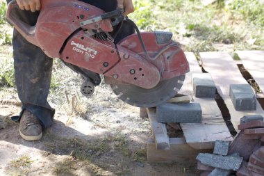İnşaat işçisi elektrik kesicisiyle beton tuğla kesiyor. Belarus, Minsk, 2016