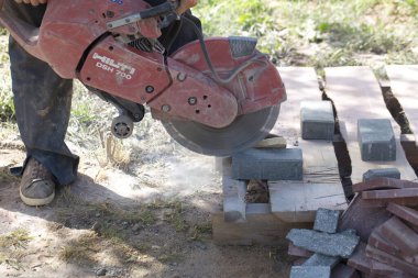 İnşaat işçisi elektrik kesicisiyle beton tuğla kesiyor. Belarus, Minsk, 2016