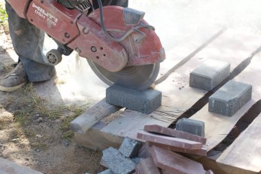 İnşaat işçisi elektrik kesicisiyle beton tuğla kesiyor. Belarus, Minsk, 2016