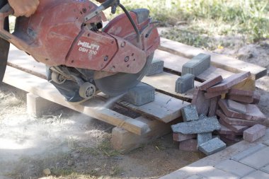 İnşaat işçisi elektrik kesicisiyle beton tuğla kesiyor. Belarus, Minsk, 2016