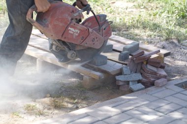 İnşaat işçisi elektrik kesicisiyle beton tuğla kesiyor. Belarus, Minsk, 2016