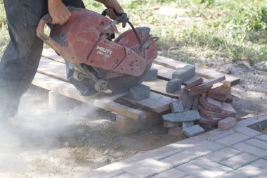 İnşaat işçisi elektrik kesicisiyle beton tuğla kesiyor. Belarus, Minsk, 2016