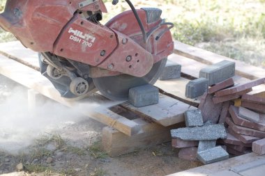 İnşaat işçisi elektrik kesicisiyle beton tuğla kesiyor. Belarus, Minsk, 2016