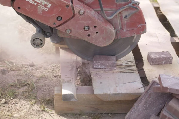 İnşaat işçisi elektrik kesicisiyle beton tuğla kesiyor. Belarus, Minsk, 2016