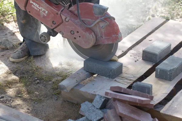 İnşaat işçisi elektrik kesicisiyle beton tuğla kesiyor. Belarus, Minsk, 2016