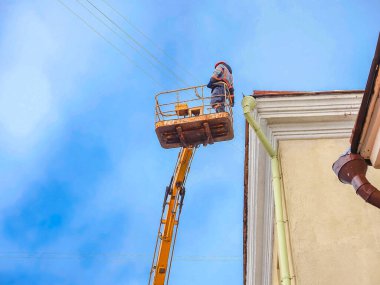 Beyaz Rusya, Minsk, 2022. Hidrolik asansörde çalışan bir işçi buz saçaklarını bir evin çatısından düşürdü..