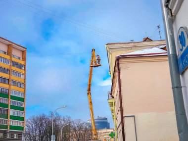 Beyaz Rusya, Minsk, 2022. Hidrolik asansörde çalışan bir işçi buz saçaklarını bir evin çatısından düşürdü..