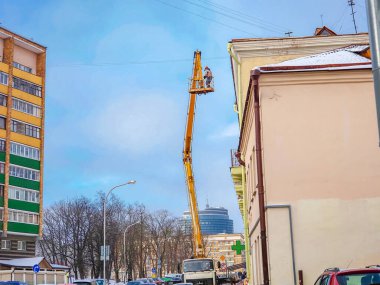 Beyaz Rusya, Minsk, 2022. Hidrolik asansörde çalışan bir işçi buz saçaklarını bir evin çatısından düşürdü..