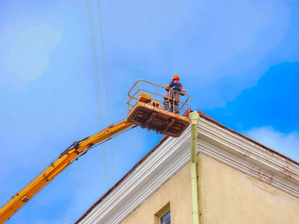 Beyaz Rusya, Minsk, 2022. Hidrolik asansörde çalışan bir işçi buz saçaklarını bir evin çatısından düşürdü..