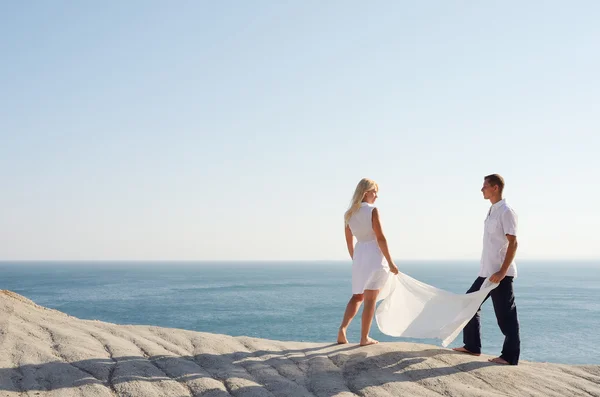 Menino e menina segurando um xale branco, perto do mar — Fotografia de Stock