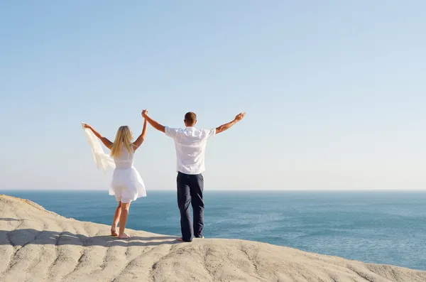 Junges Paar auf einem Felsen hob die Hände in den Himmel — Stockfoto