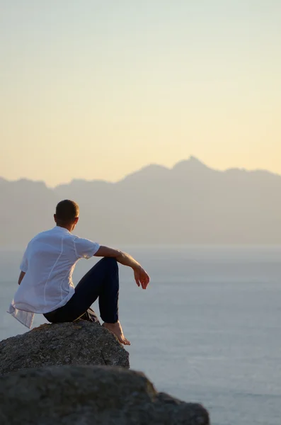 El hombre se sienta sobre una piedra — Foto de Stock