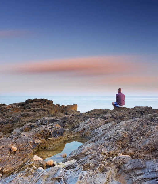 Killen sitter på en klippa vid havet — Stockfoto