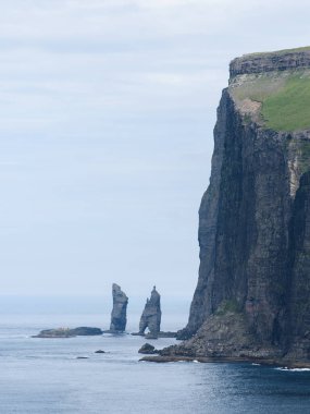 Faroe Adaları 'ndaki Tjornuvik köyünden Risin og Kellingin deniz yığınlarının manzarası. Bulutlu kuzey havası