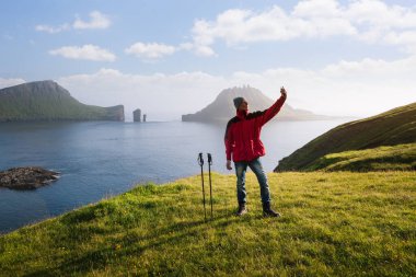 Turist, Drangarnir ve Tindholmur 'un arka planında selfie çekiyor. Gasadalur, Faroe Adaları 'na giden eski posta yolu.